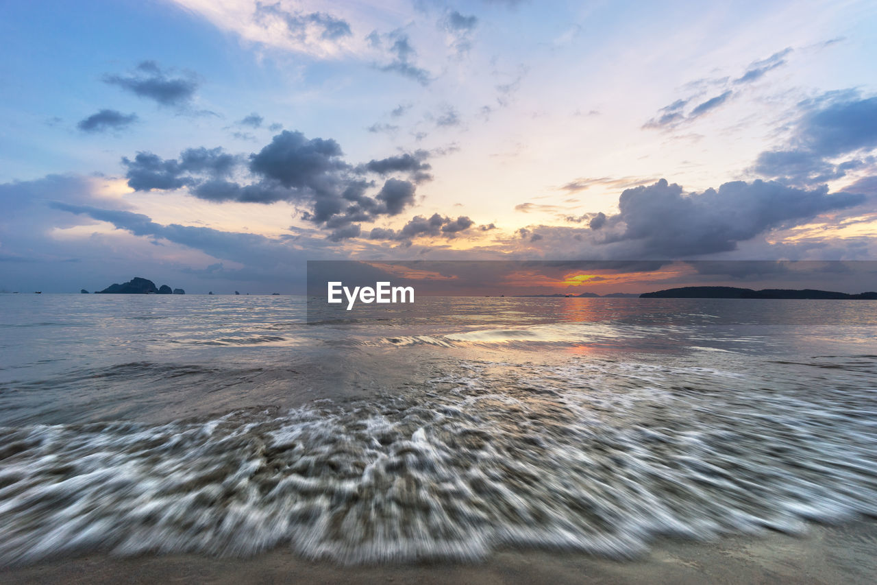 Amazing seascape with wave of water, dramatic clouds on horizon and picturesque sunset 