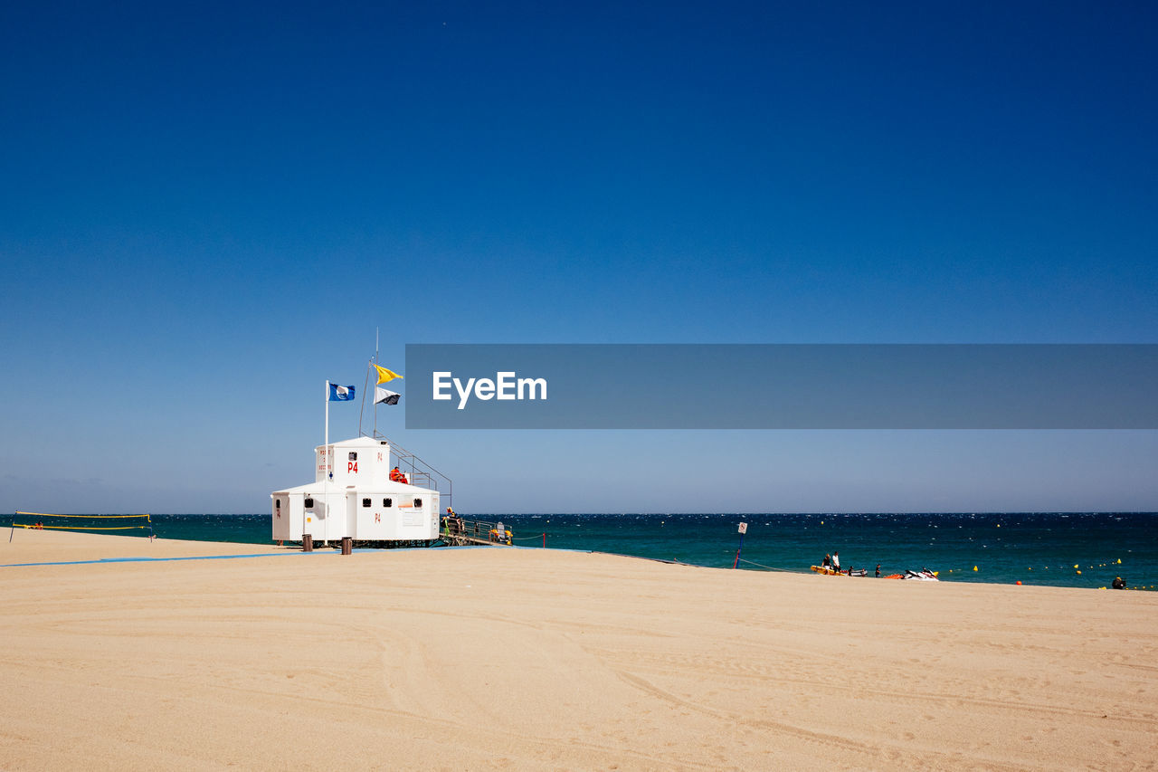 Life guard hut on beach against clear blue sky