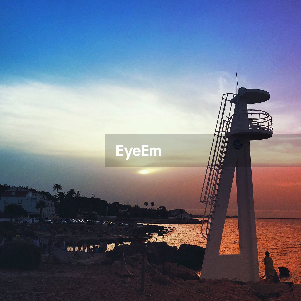 Lookout tower by sea against sky during sunset