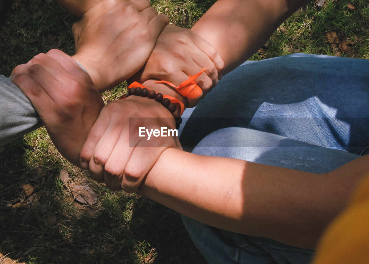 HIGH ANGLE VIEW OF PEOPLE HANDS ON ROCK