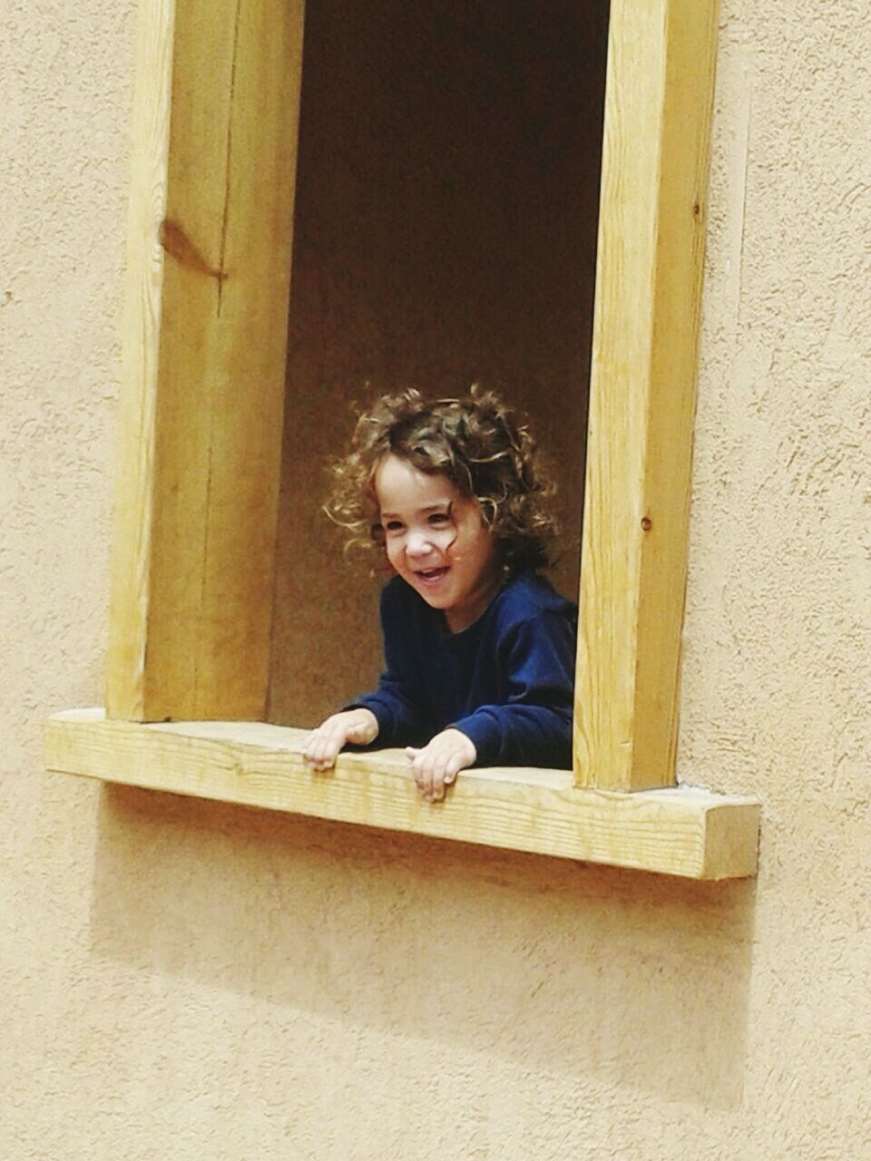 Smiling cute boy standing on house window