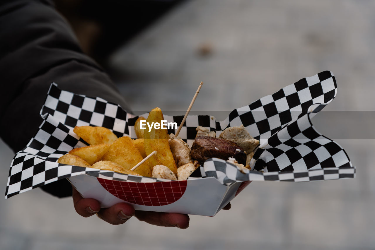 Cropped image of woman hand holding meat with french fries