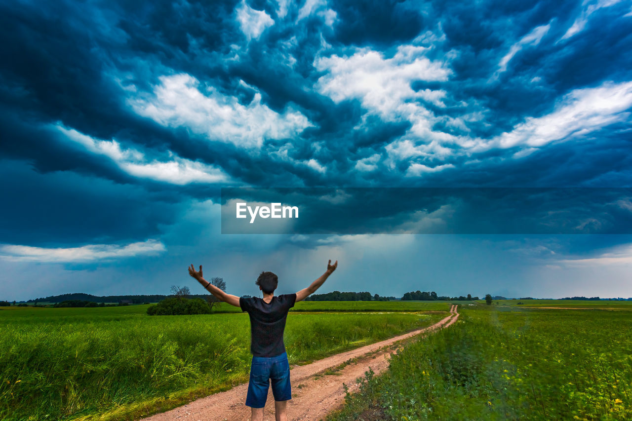 Rear view of man standing on land against sky