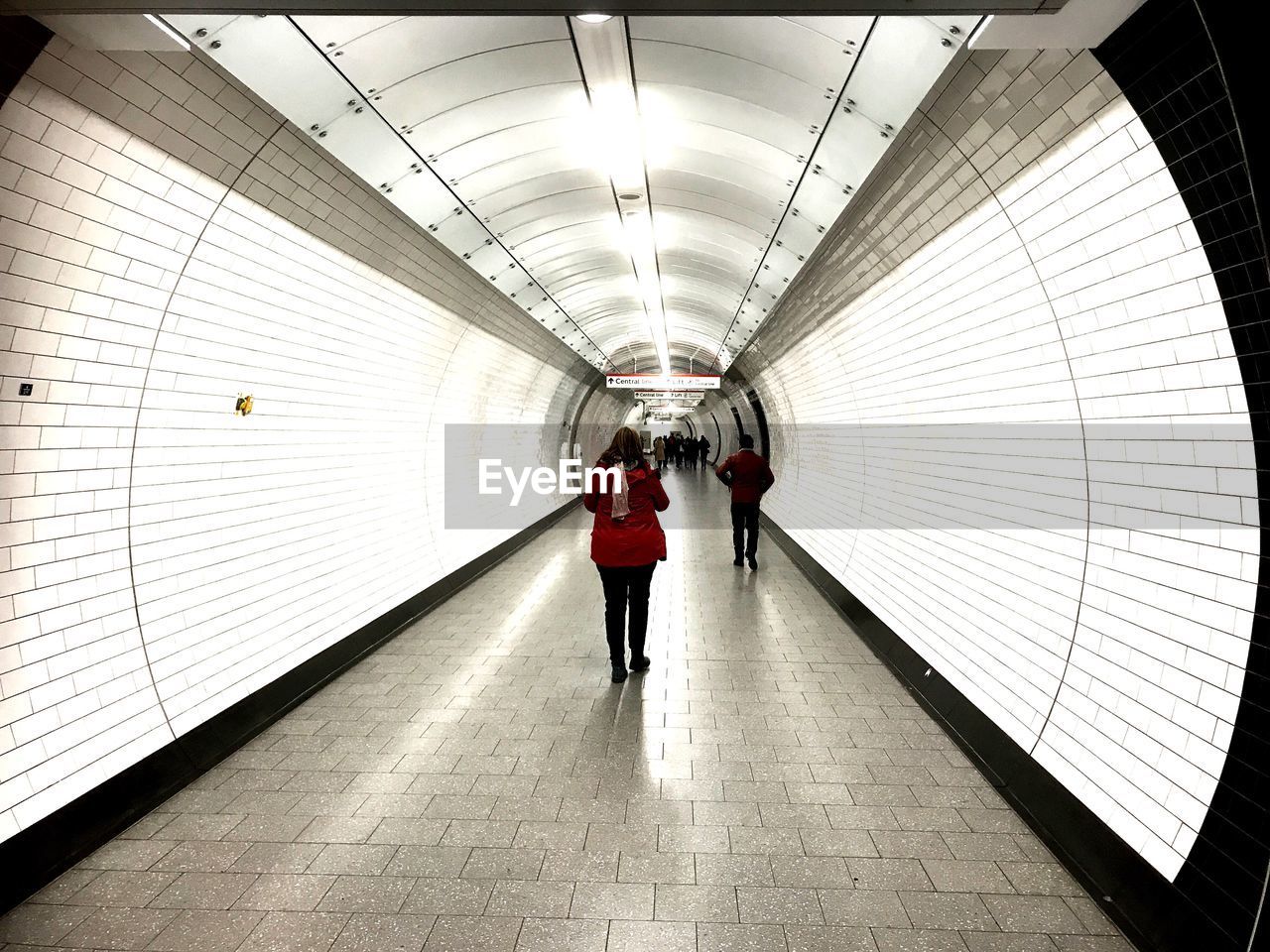 REAR VIEW OF PEOPLE ON ILLUMINATED WALKWAY