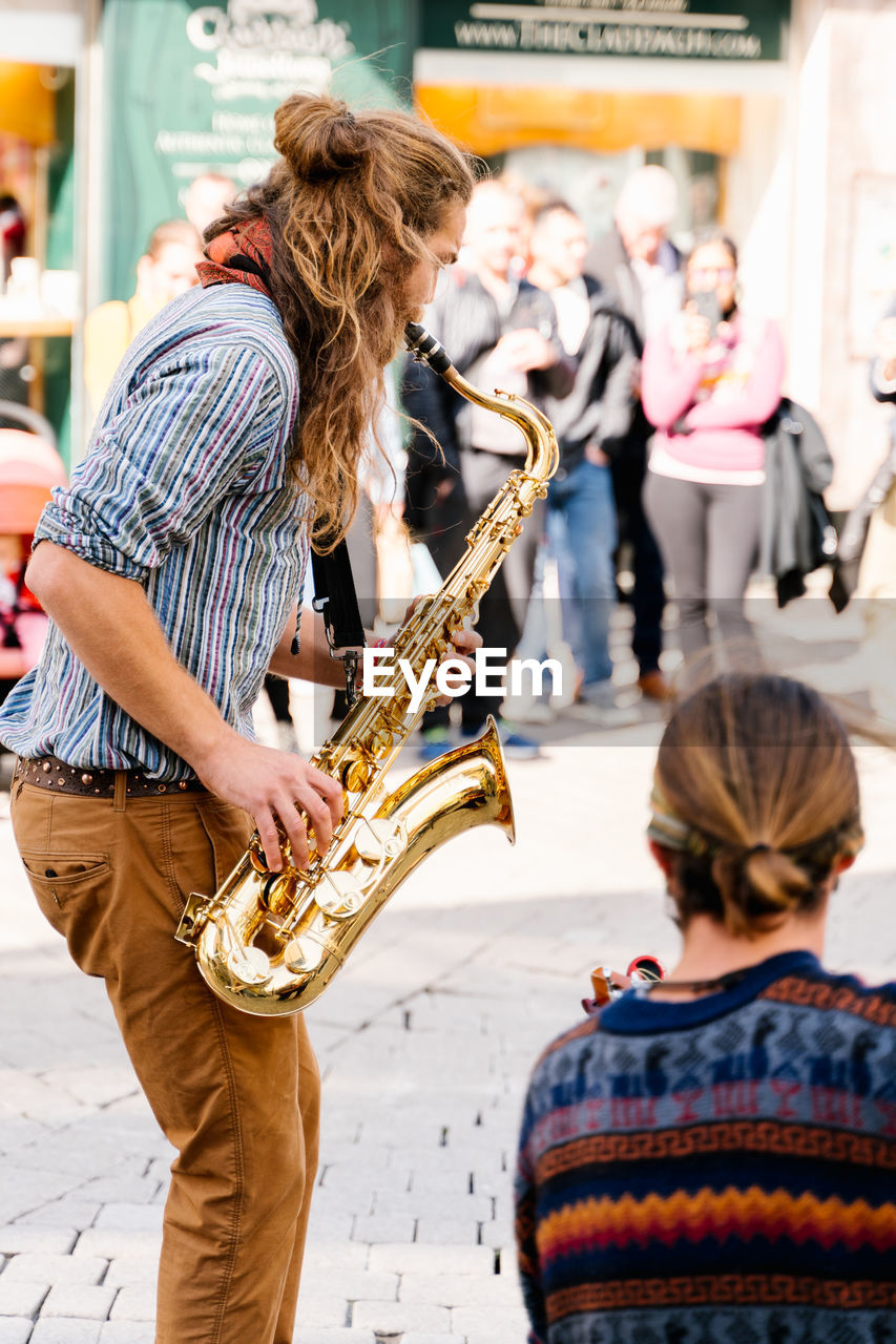 Saxophone player on his back playing next to a guitarist on the street