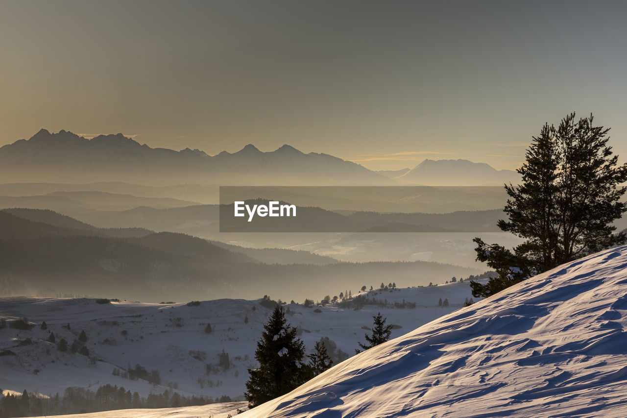 Scenic view of snow covered mountains against sky during sunset