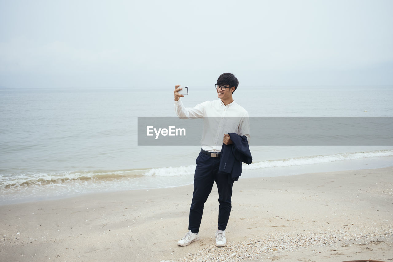 FULL LENGTH OF BOY STANDING ON BEACH