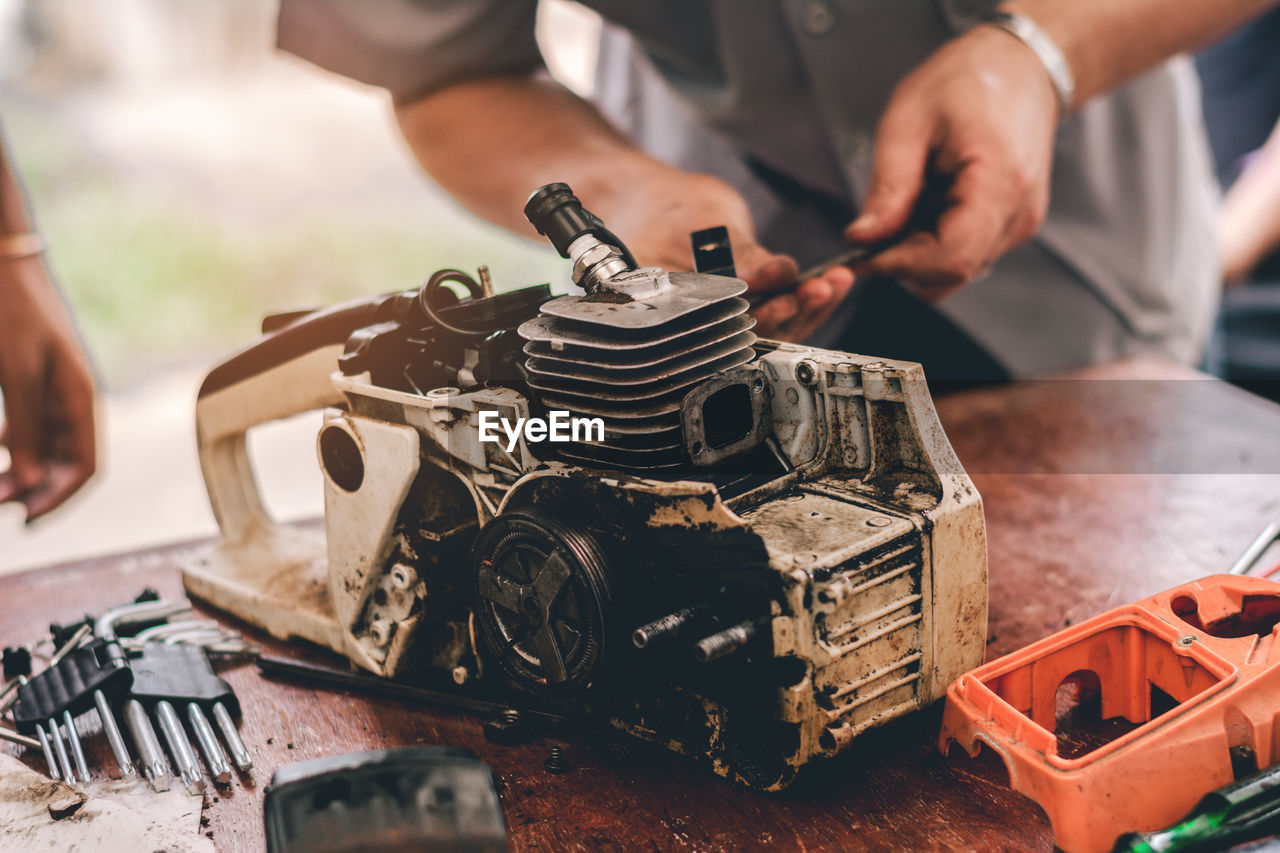 Close-up of mechanic repairing machinery on workbench in workshop