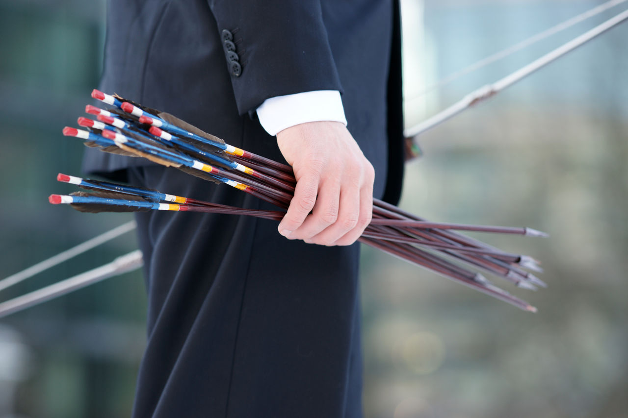 Midsection of person holding arrows