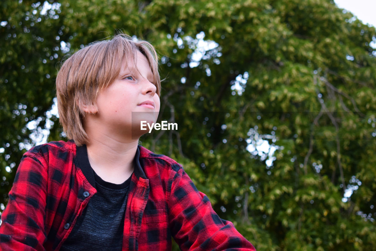 Portrait of boy looking away against trees