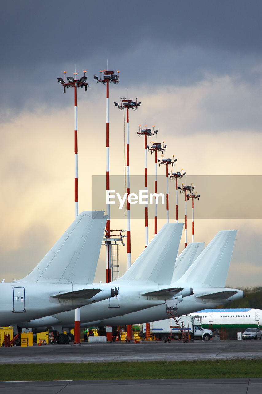 Aircraft tails parked at airport apron against  cloudy sky