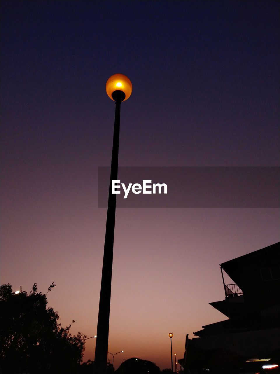 Low angle view of illuminated street light against sky at dusk