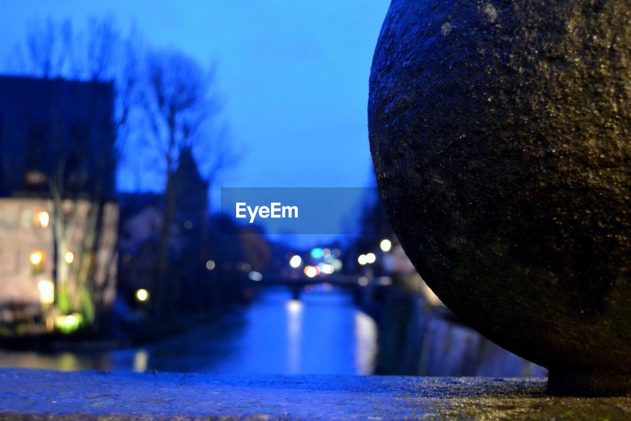 Close-up of stone with canal in background at dusk