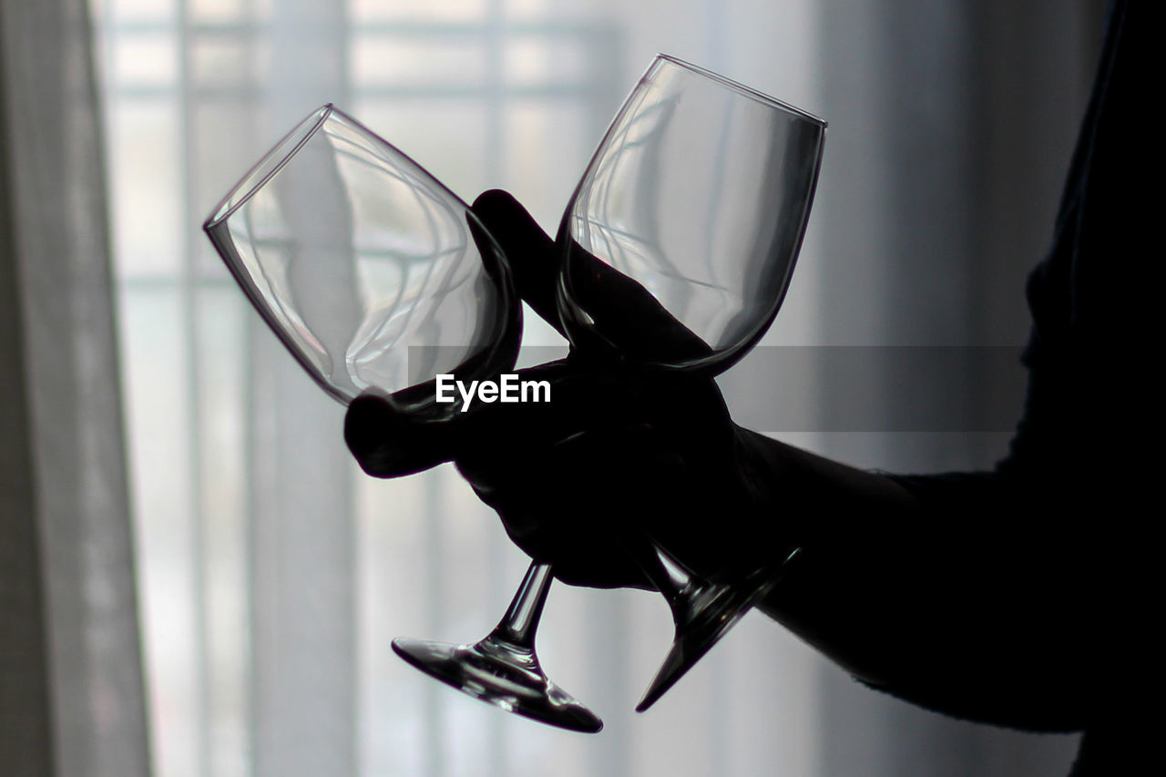 Cropped image of silhouette person holding wineglasses