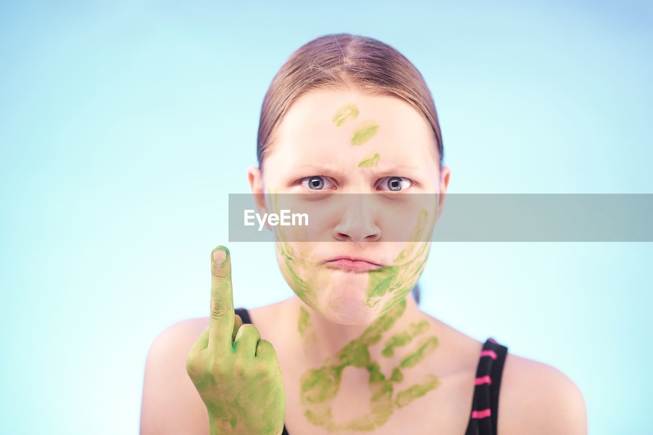 Aggressive woman showing middle finger against blue background