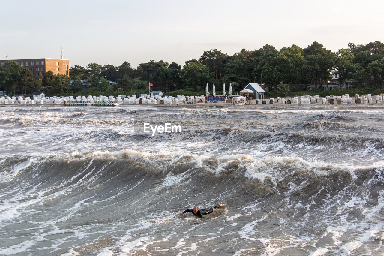 PEOPLE ON SHORE AGAINST SKY