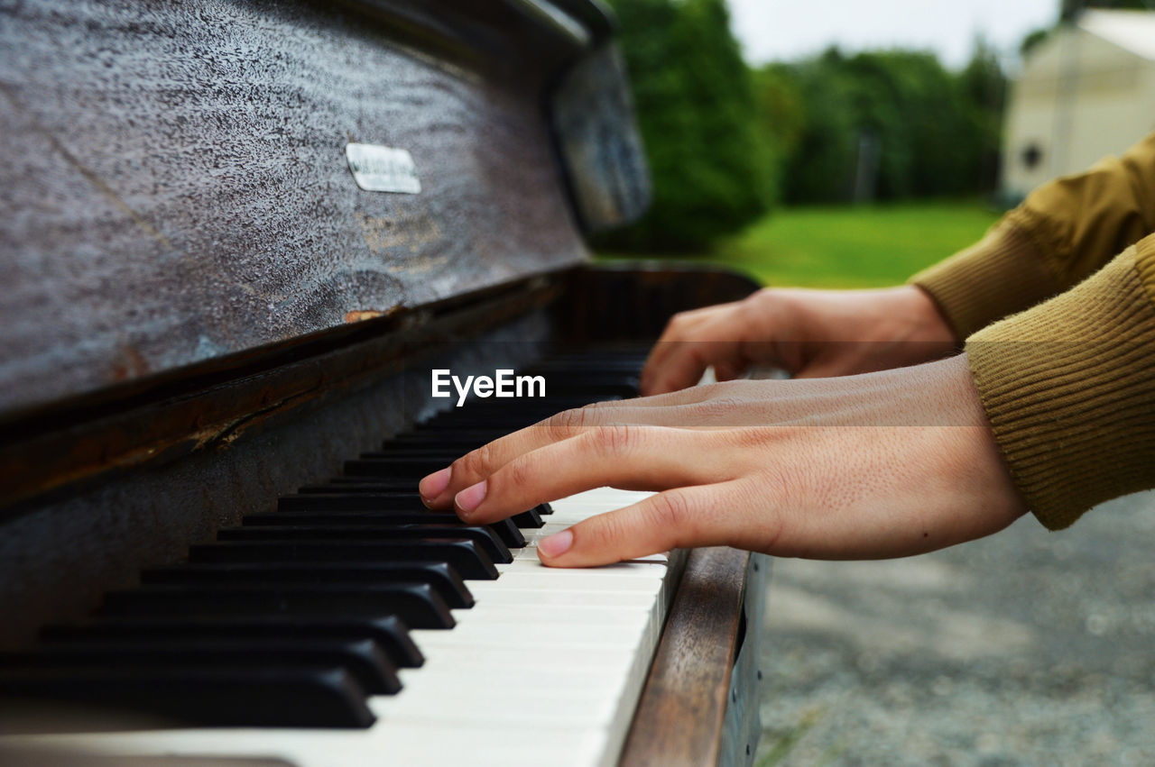 Close-up of hands playing piano outside in nature 