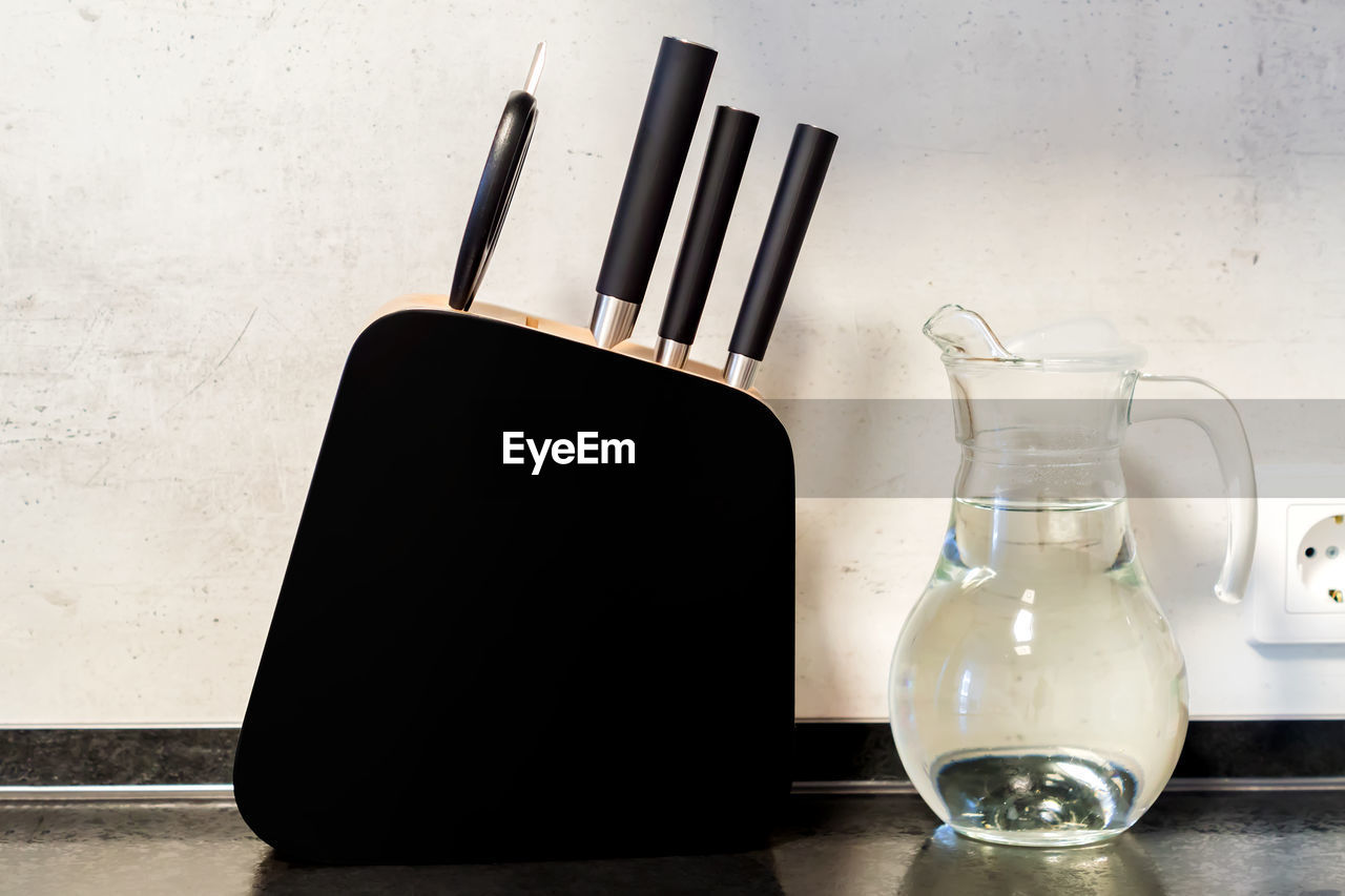 Modern black and white kitchen - black wooden stand for knives and transparent glass jug of water