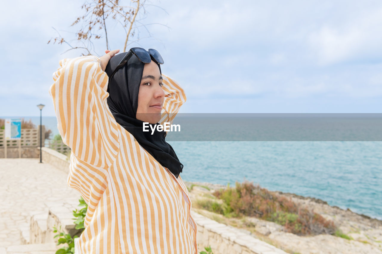 Maghrebi woman with hijab and glasses relaxing near the sea