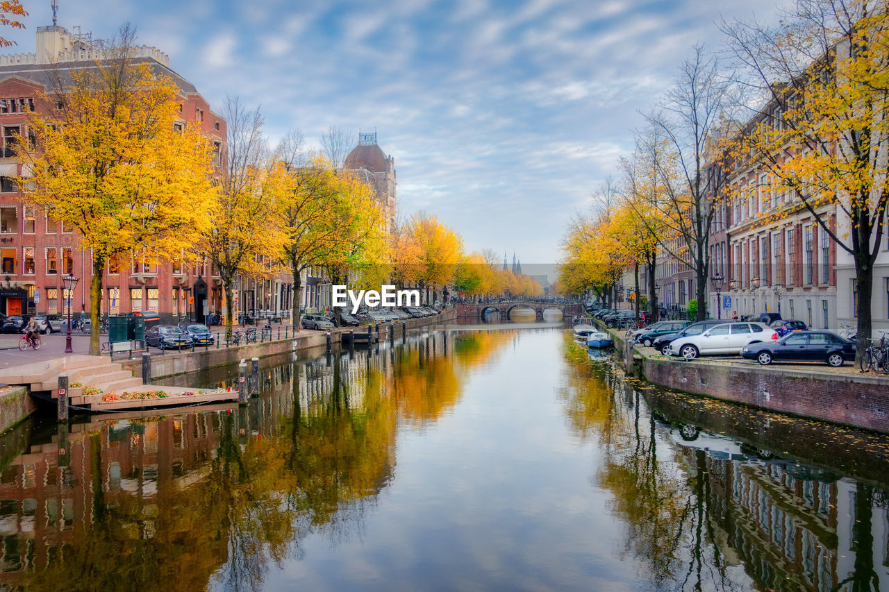 Canal amidst trees and buildings against sky during autumn