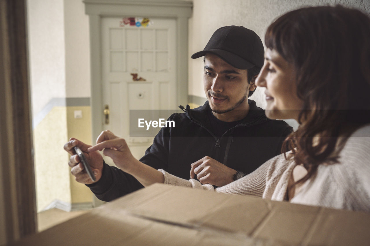 Female customer signing on mobile phone during package delivery