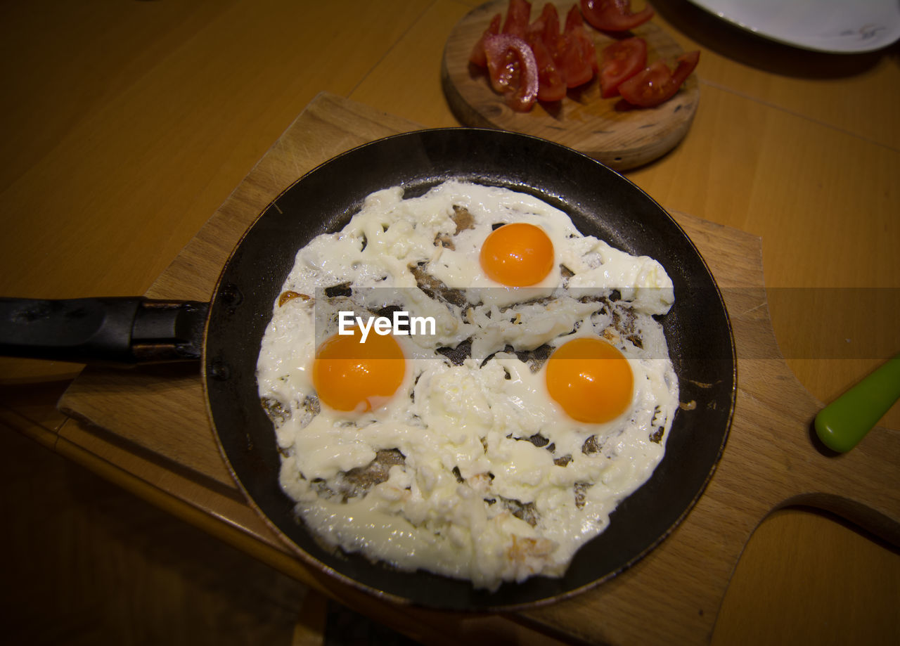 High angle view of fried egg in frying pan on cutting board at home