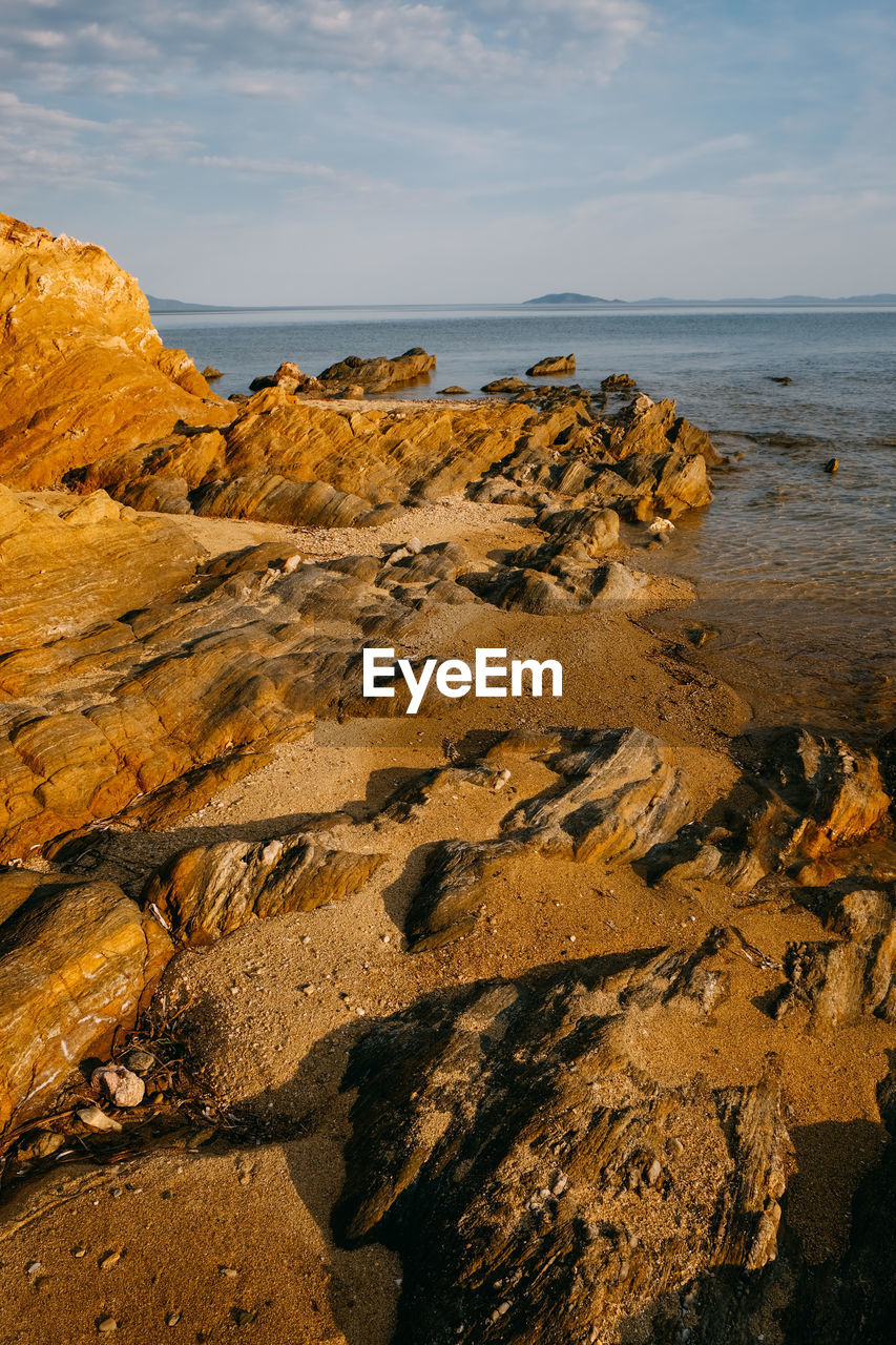 Scenic view of rocks on beach against sky