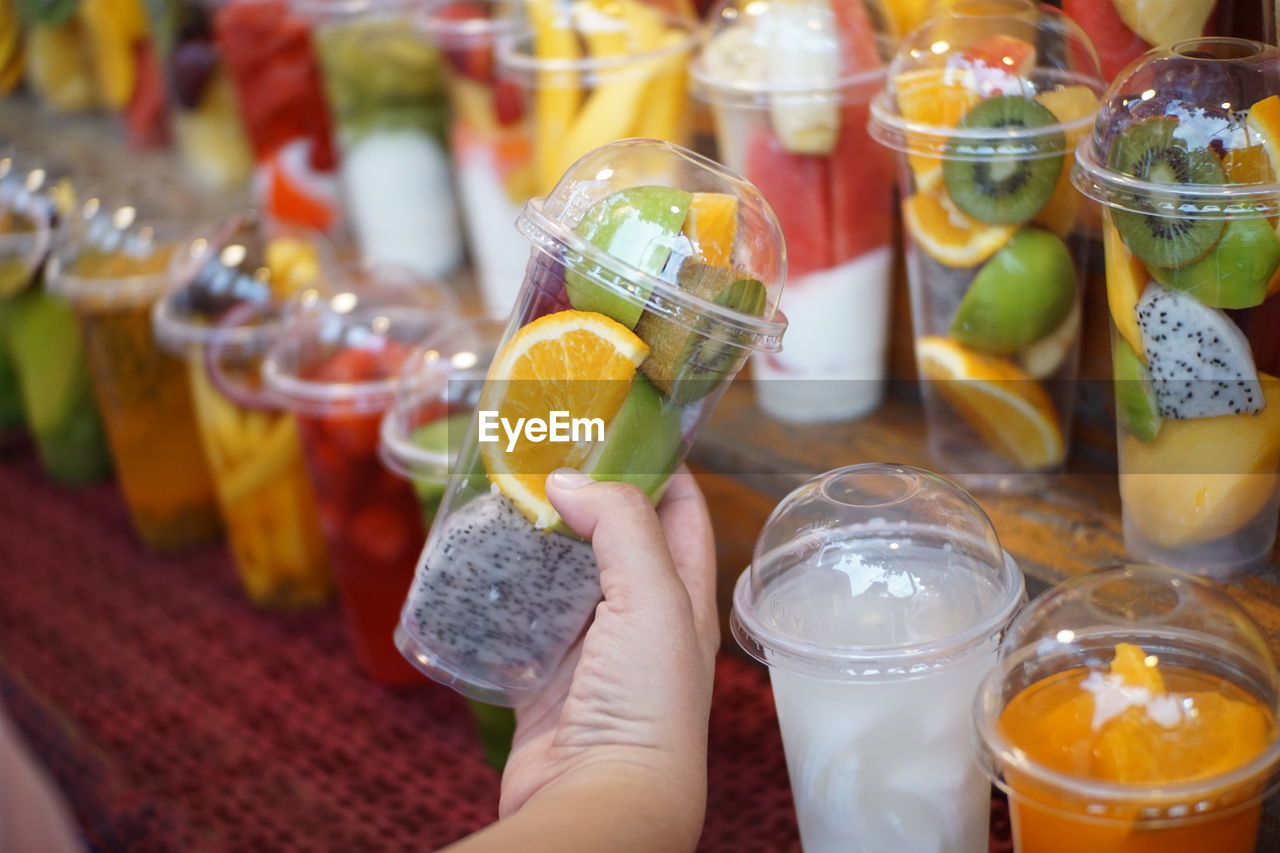 CROPPED IMAGE OF PERSON HOLDING DRINK WITH GLASS OF JUICE