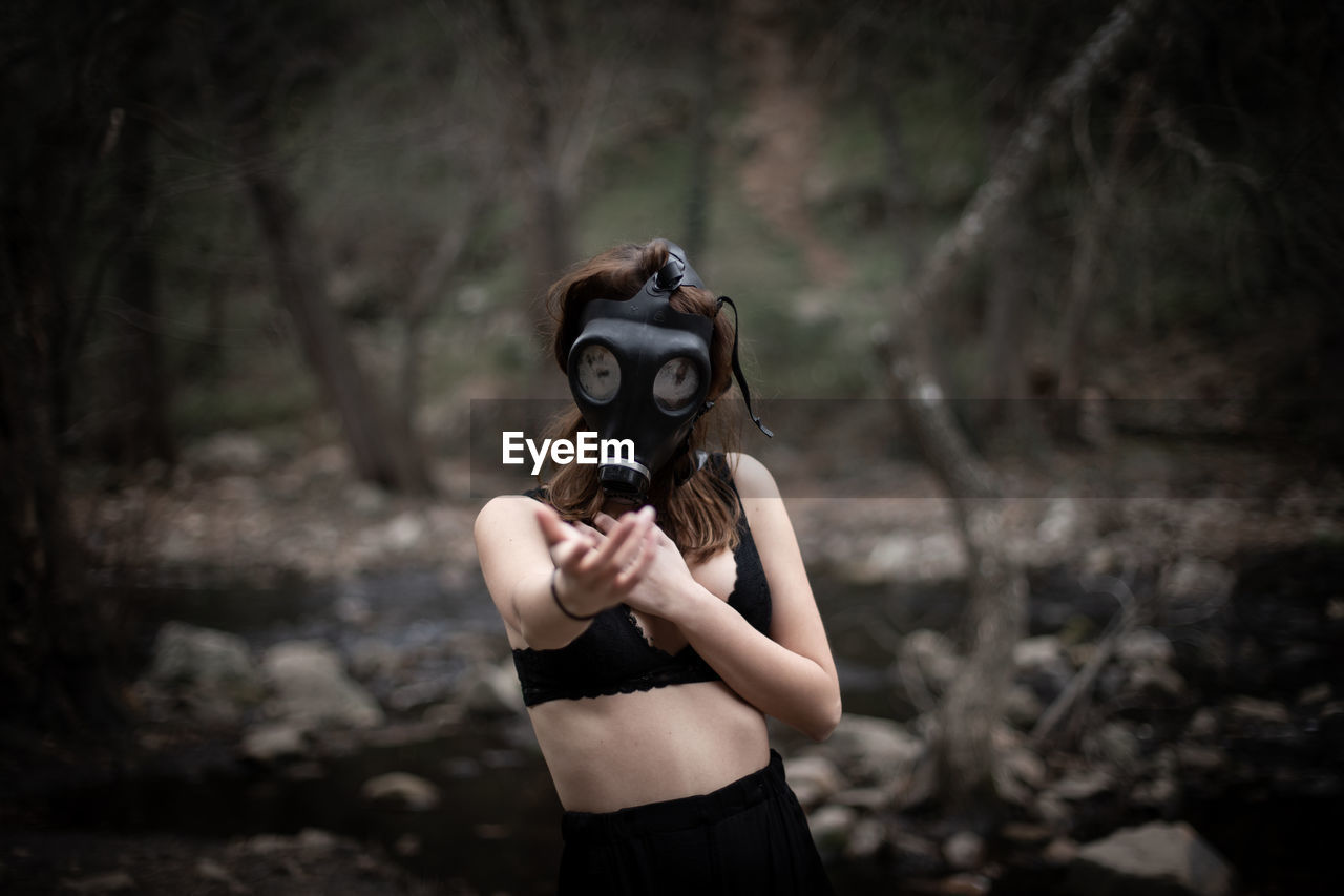 MIDSECTION OF WOMAN HOLDING CAMERA WHILE STANDING ON LAND