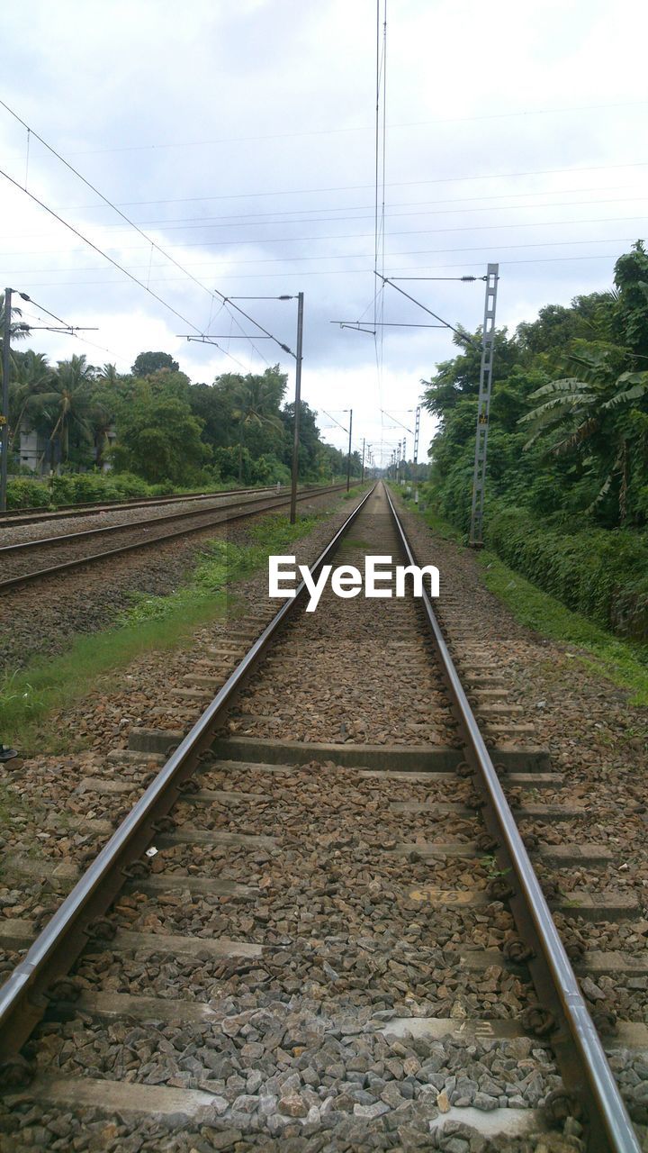 Railroad tracks against cloudy sky