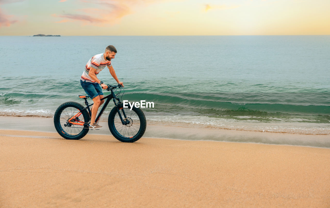 Young man riding a fat bike on the beach