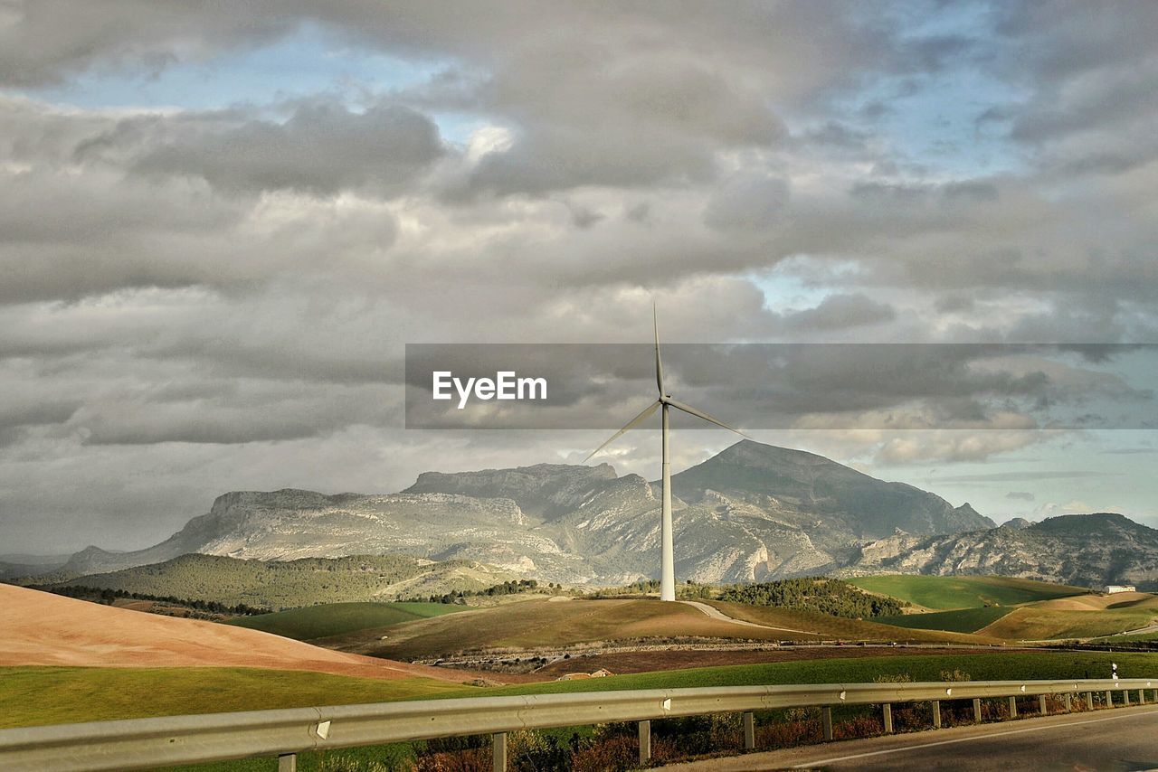 Wind turbine on countryside landscape against clouds