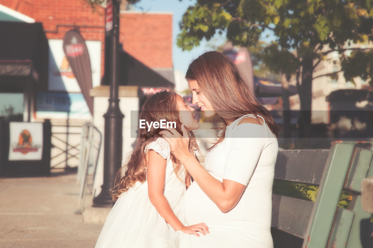 Side view of pregnant mother with daughter