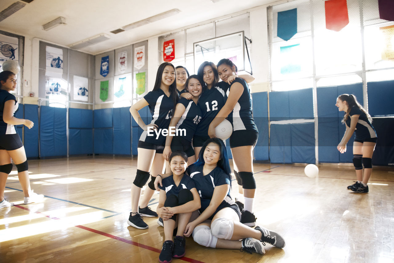 Happy teenage girls team at volleyball court