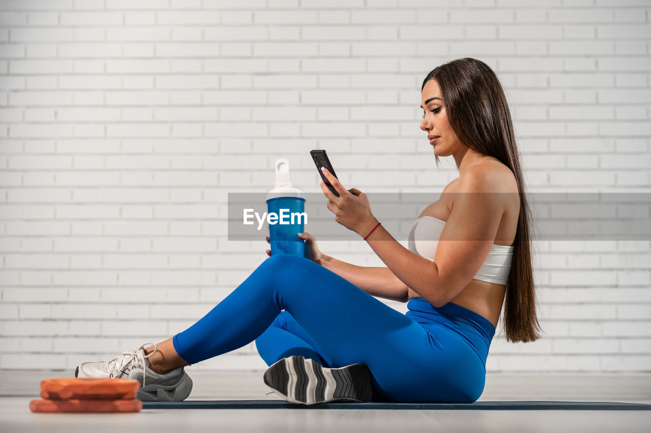 A pretty caucasian woman using mobile phone after exercising