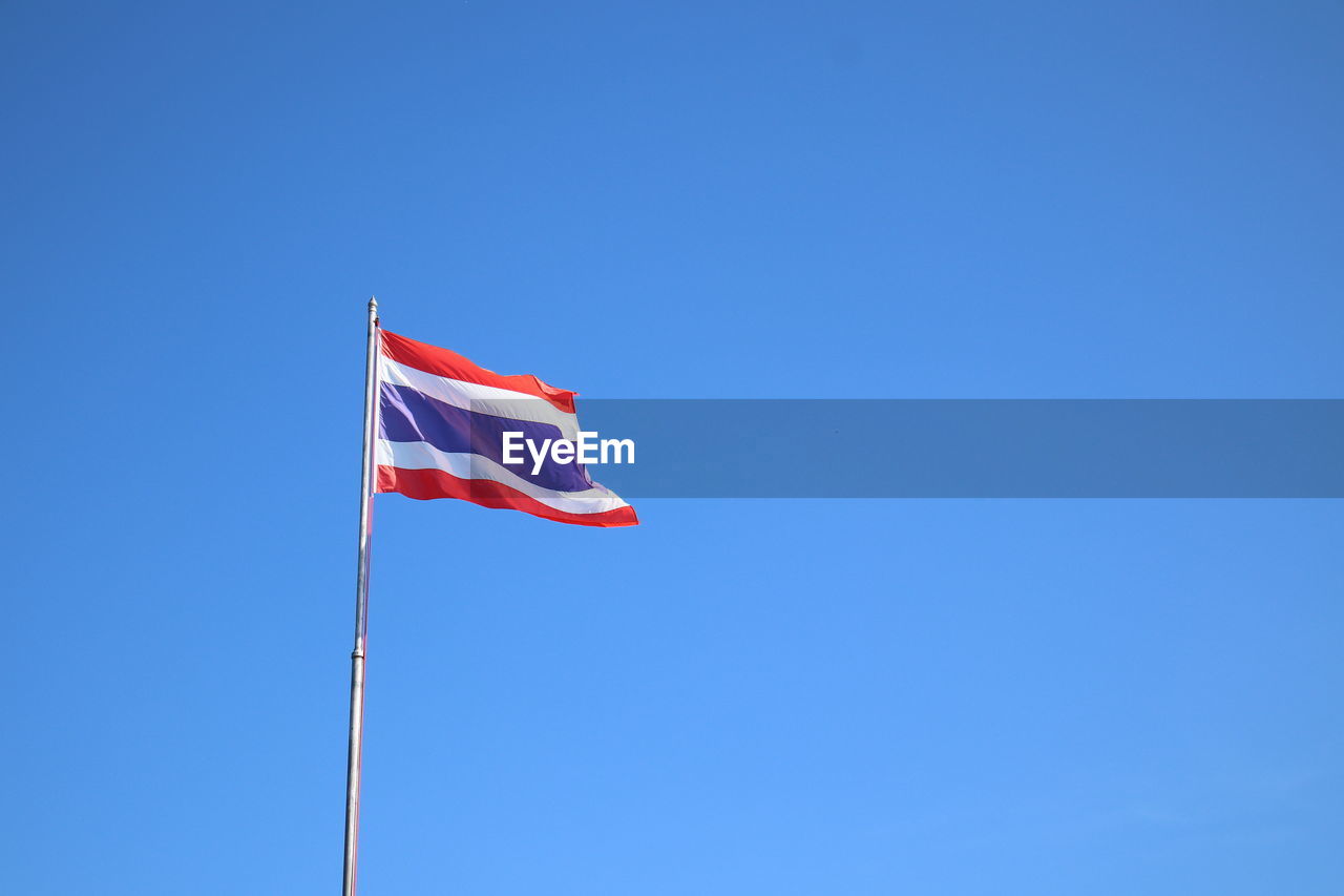 Low angle view of flag flags against clear blue sky