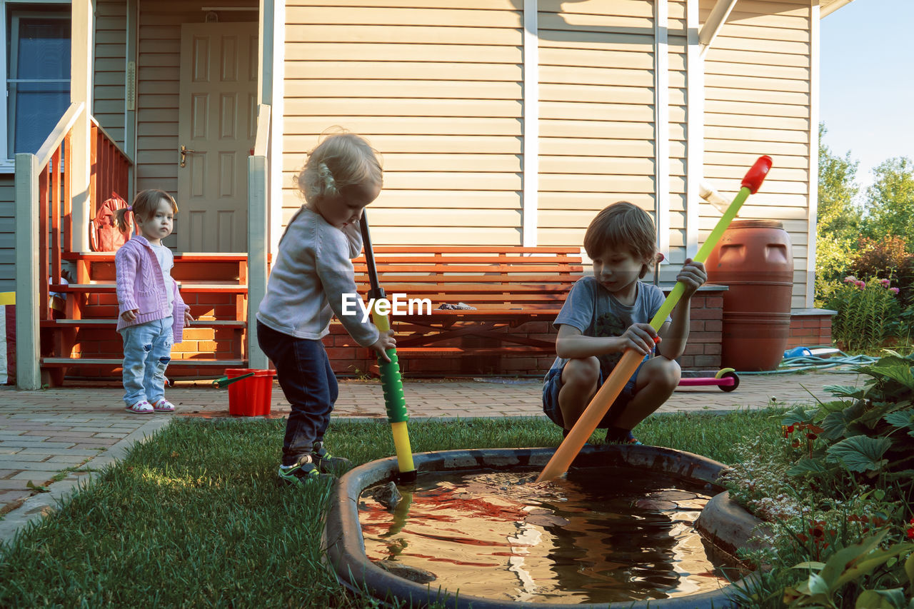 Siblings playing with toys in yard