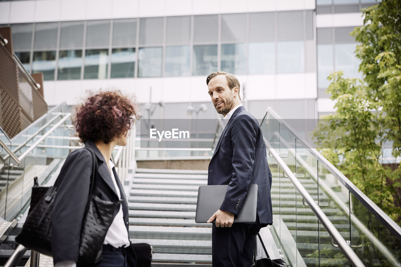 Low angle view of lawyer talking to coworker while standing on steps at office