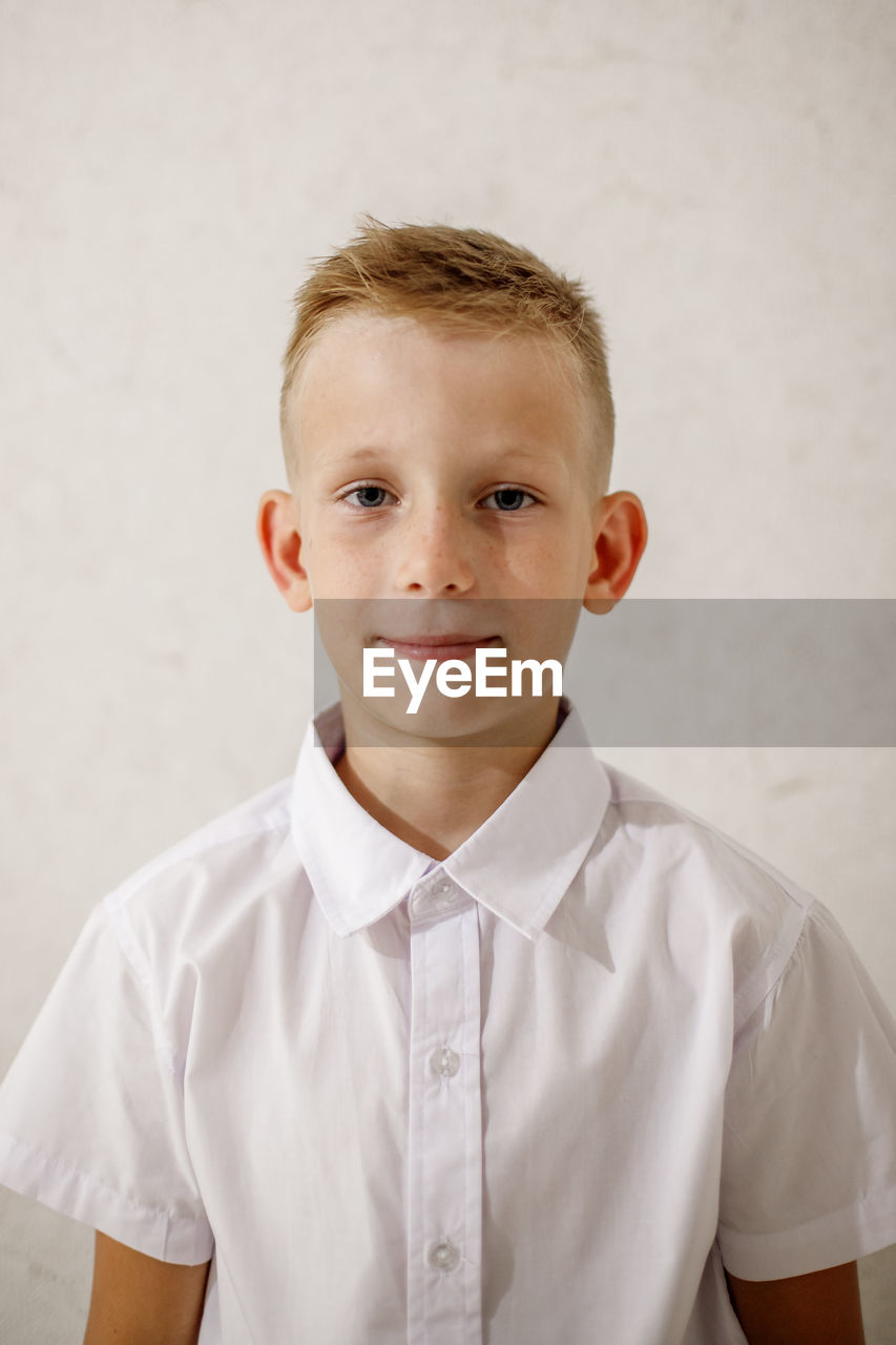 Portrait of boy standing against wall