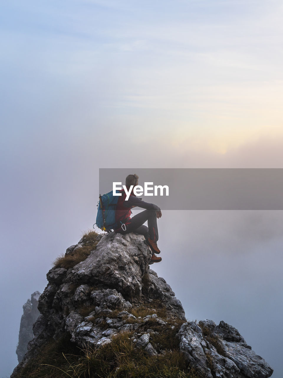 Pensive hiker sitting on mountain peak during sunrise at bergamasque alps, italy