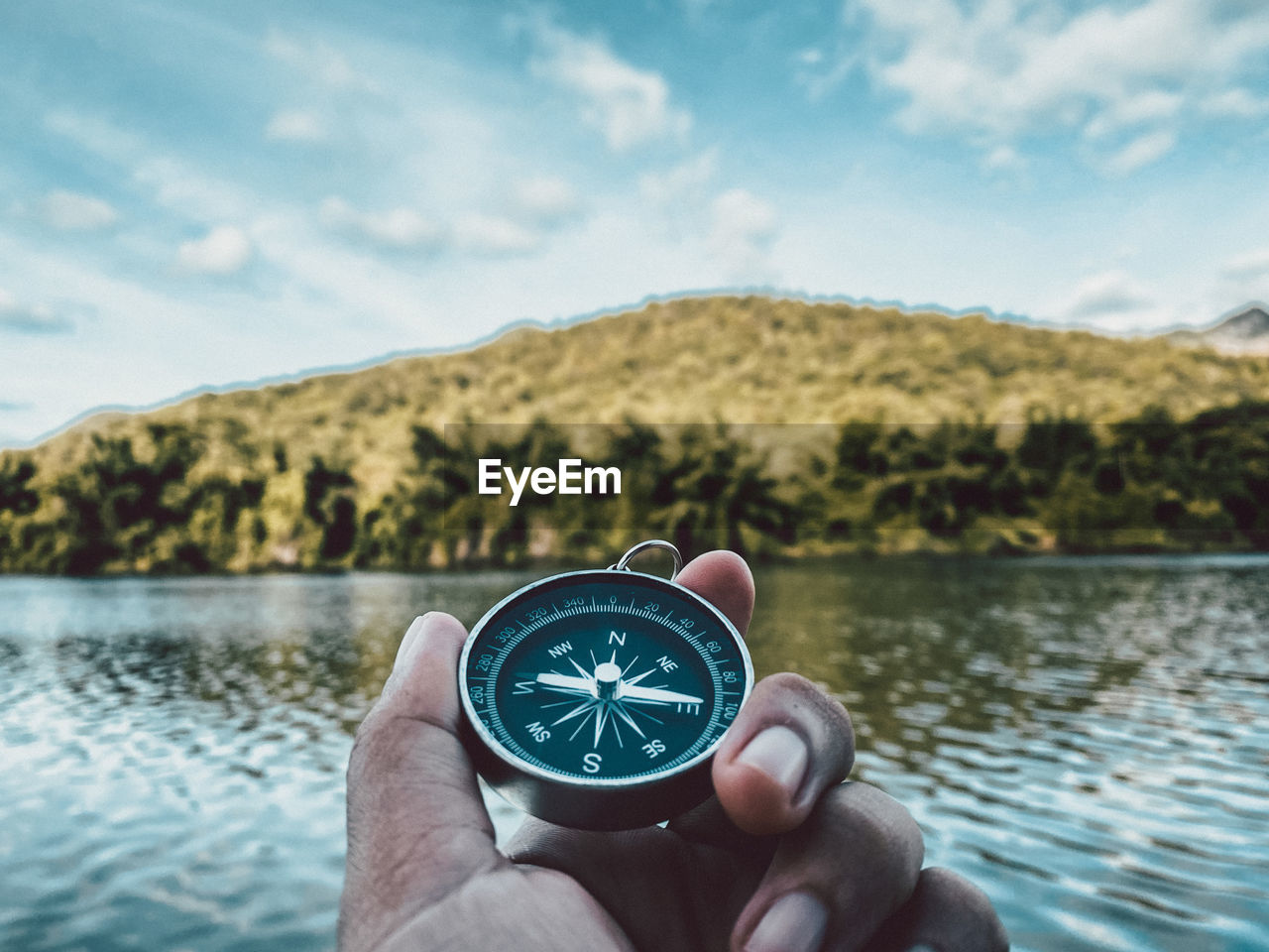 PERSON HOLDING SUNGLASSES AGAINST LAKE AND MOUNTAINS