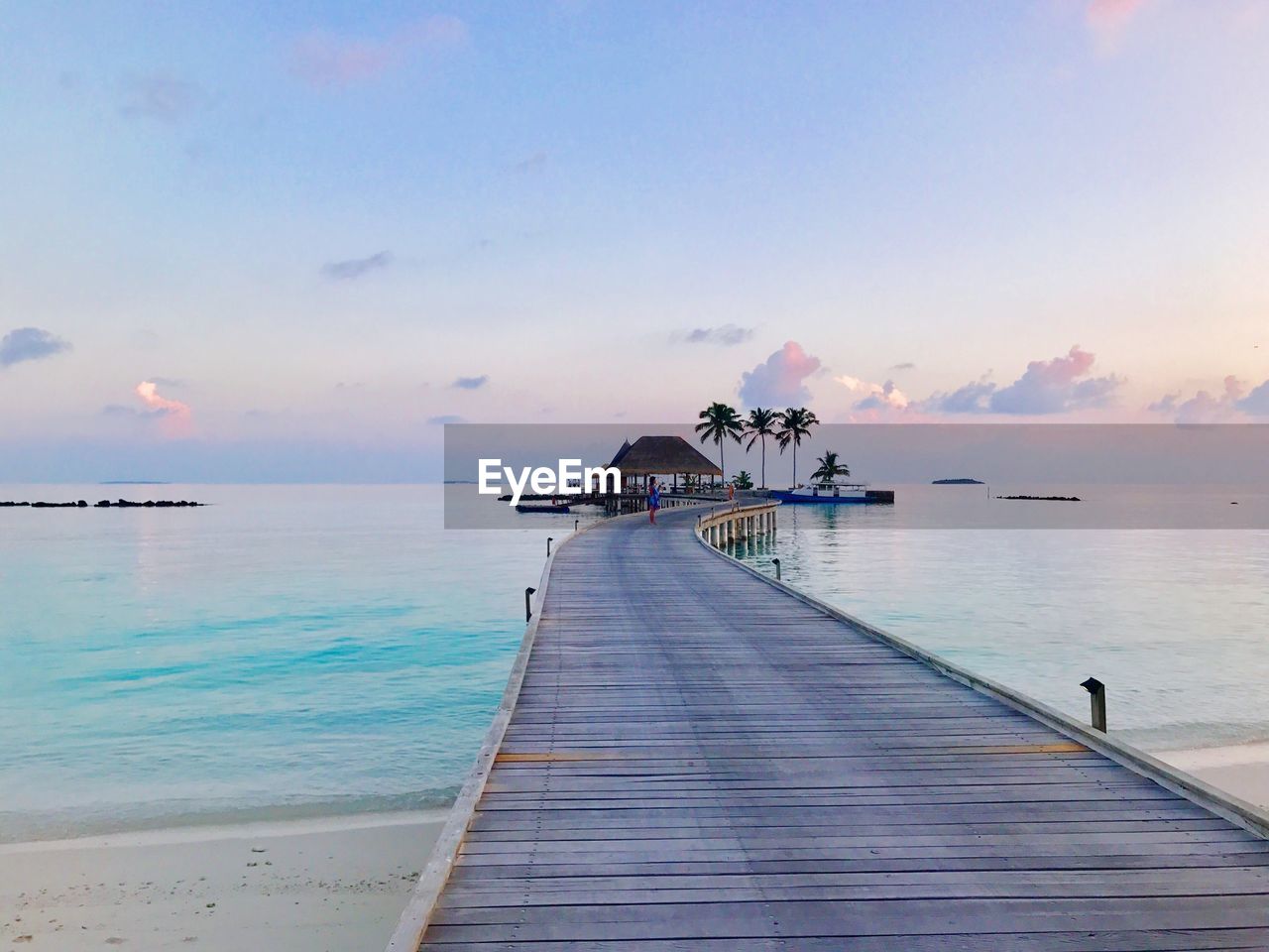 Pier amidst sea against sky during sunset