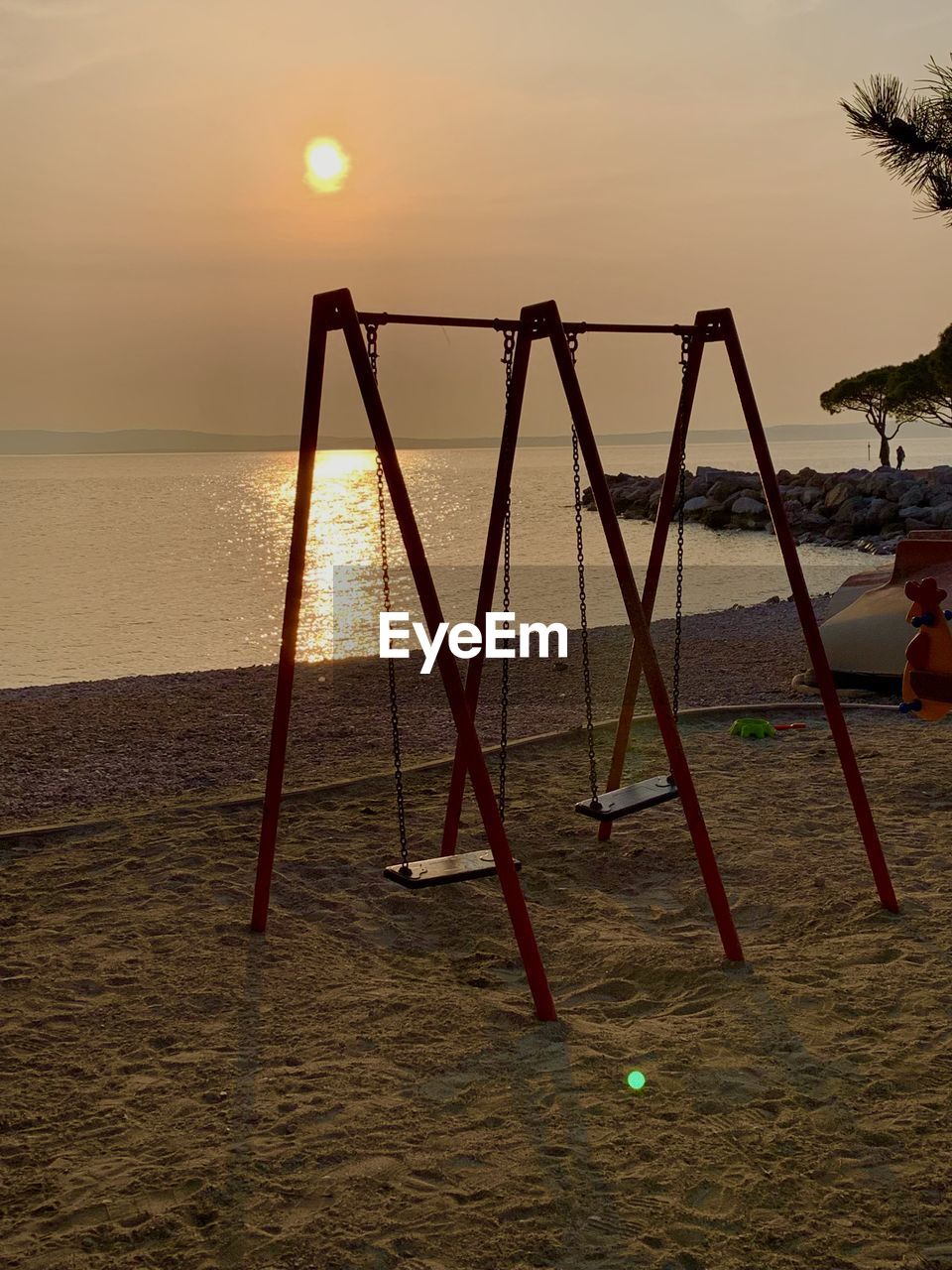 empty swing at beach during sunset