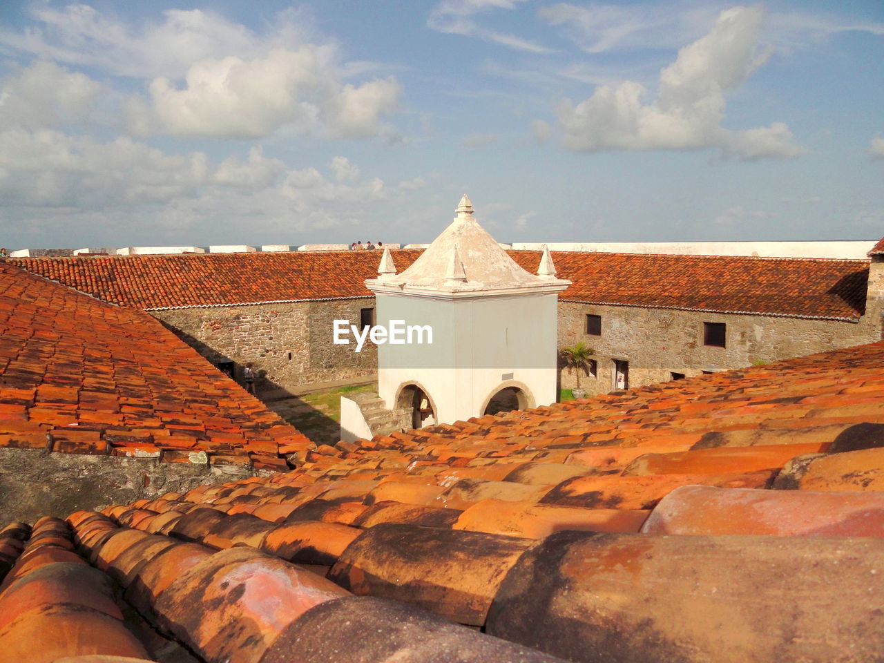 View of a building in the centre of a fortress surrounded by brown tiles against sky