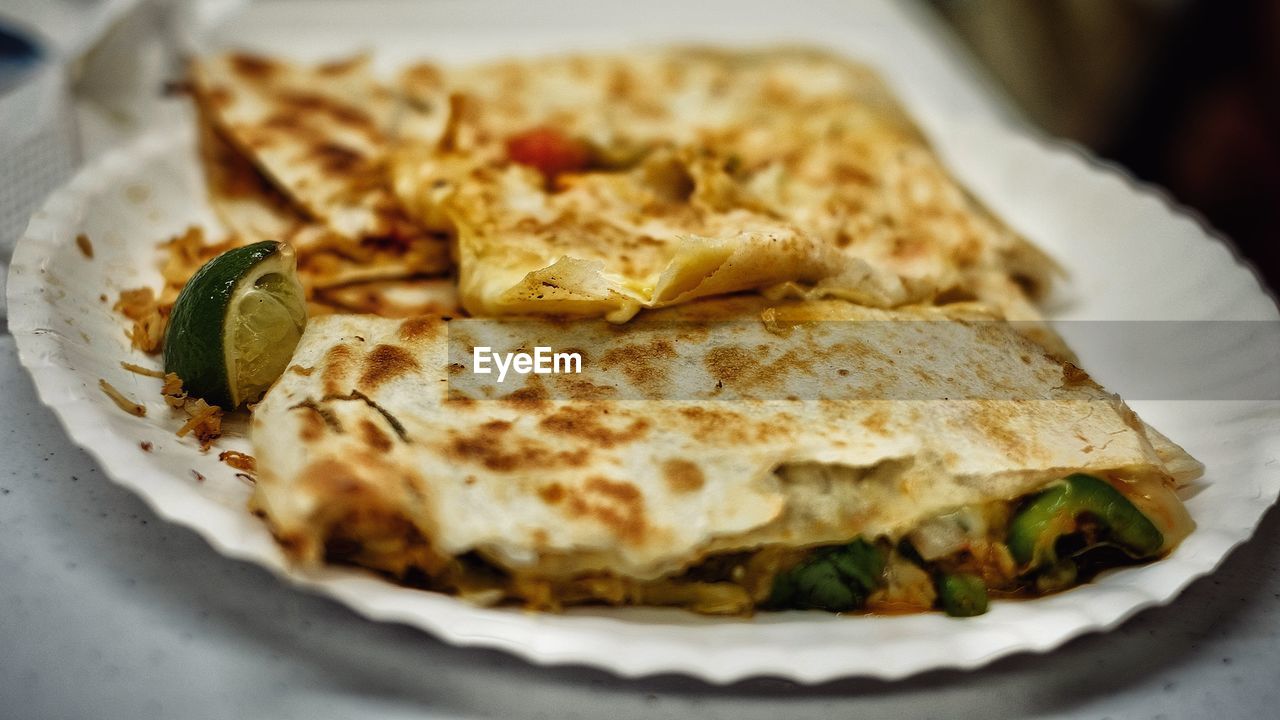 Close-up of fresh quesadilla with lemon piece served in plate