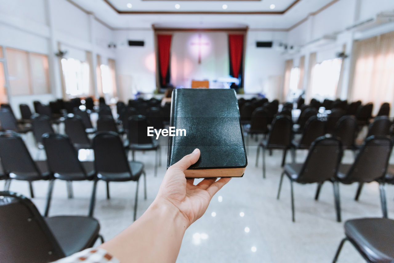 Cropped hand of woman holding bible in church