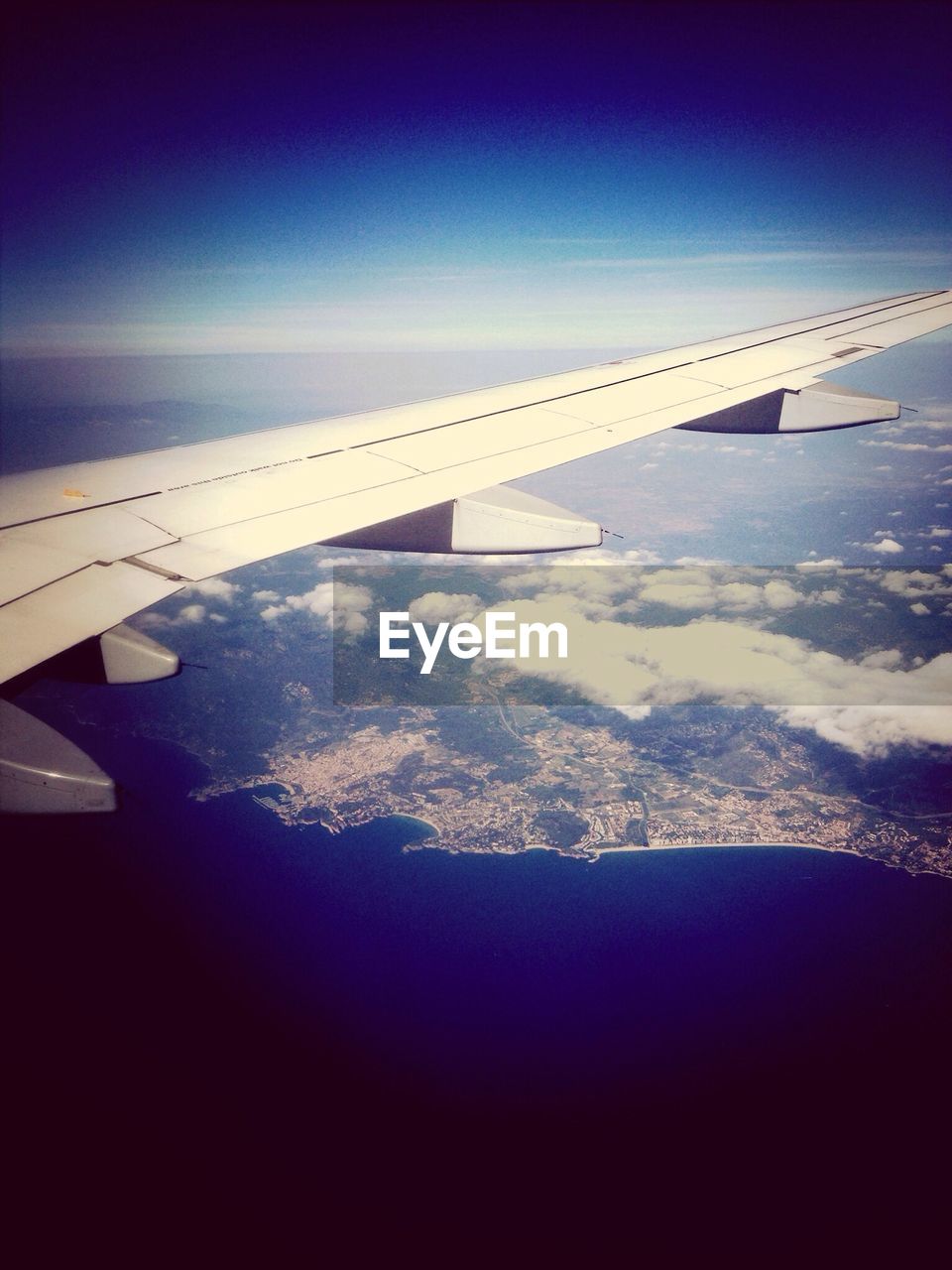 Cropped image of airplane over sea against clear blue sky