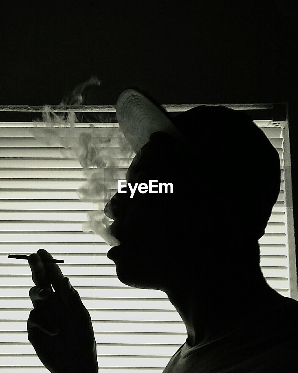 Side view of man smoking by window