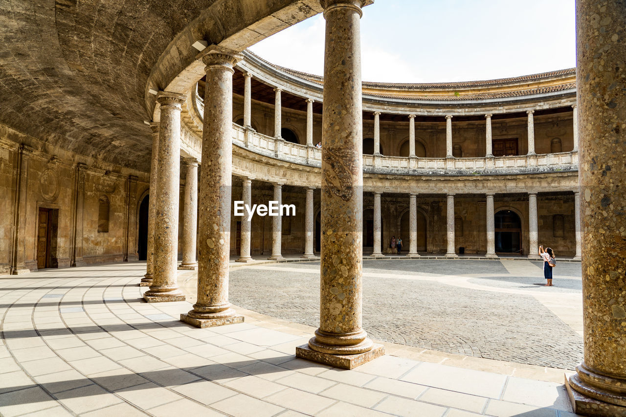 Woman photographing historic building against sky