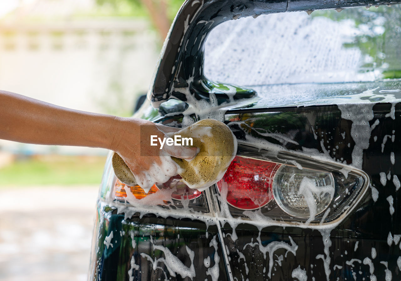 Cropped hand of woman washing car